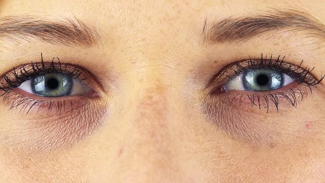 A woman opens her blue eyes - closeup