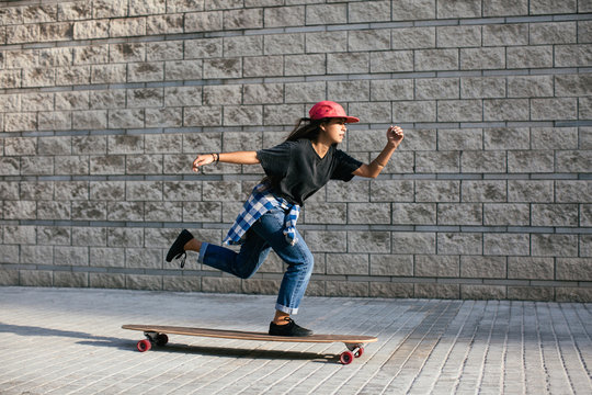 Skater girl riding on longboard on the street.