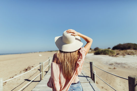woman with hat  standing idle of the  wooden bridge