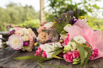 Wedding bouquet with pink, white and violet flowers - set on a wooden table. 