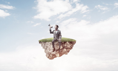 Businessman floating on island in sky and announcing something i