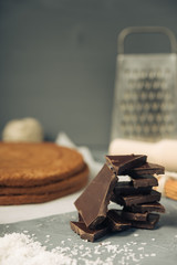 Dark chocolate and biscuit cake layer. Chocolate bar in foil on grey background. Copy space