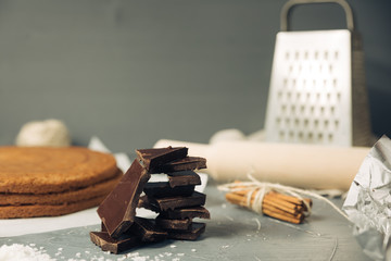 Dark chocolate and biscuit cake layer. Chocolate bar in foil on grey background. Copy space