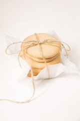 Homemade sugar cookies with honey. Ginger breads with bakery paper tied with a rope on white background