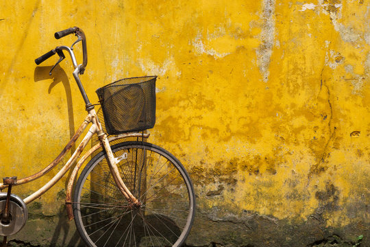 Old bicycle against old yellow wall on a street of Hanoi old town, Vietnam.