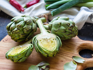 Naklejka premium Ripe artichokes on the board are whole and cut in half on the kitchen table