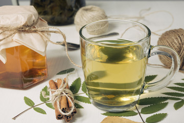 Cup of green tea with autumn leaves. Glass of hot drink on white wooden table. Fall concept