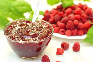 Raspberry jam in a bowl and fresh berries on the table