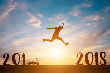 Silhouette of happy man jump between 2017 and 2018 years in sunset.