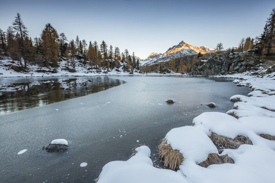 Sasso Moro peak at dawn reflects itself on the iced waters of Muful&eacute; Lake. Valmalenco, Valtellina, Sondrio, Lombardy, Italy, Europe.