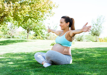 Naklejka na ściany i meble Happy pregnant woman doing yoga and meditation exercises