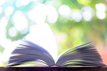 Open book on wooden table on natural background