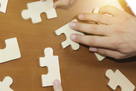 Business partnership or teamwork concept with a business people presenting a matching puzzle piece as they cooperate on finding an answer and solution, close up of their hands. 