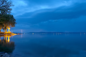 lightning bolts and storm clouds over Balaton lake in summer, in night, at low light