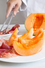 chef preparing dish with melon and ham