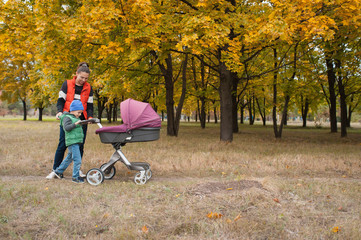 Mother walking with a baby pram in the park.