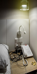 Luxury hotel room with nightstand - coin changes, hotel phone and multiple chargers in the power outlets
