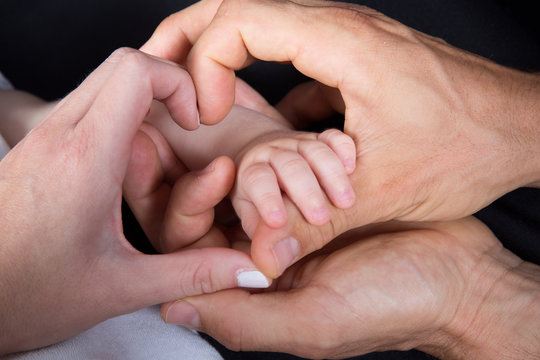father and mother hold in their hands a little newborn baby hand