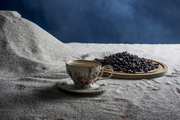 Black coffee on white sand and blue background