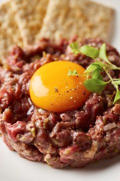 Peppered tartare made of beef with egg yolk and herb on top