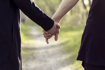 Close up of a couple holding hands in green park
