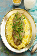 Baked pork tenderloin in herbs, with mashed potatoes and garnish.