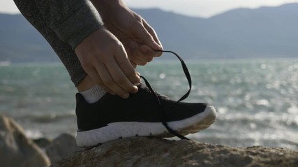 Sports woman getting ready for run tying laces of running shoes on the beach