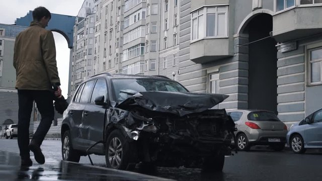 Saint Petersburg, Russia - August 3, 2017, Crashed car after accident stand at road side. Young man standing near crashed car.
