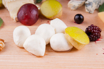 Cheese platter with fruit on a wooden board
