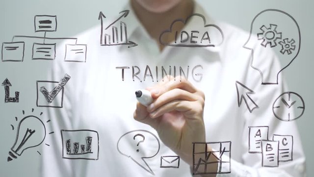Businesswoman writing TRAINING COURSE on transparent screen.