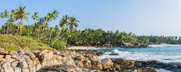 Panoramic view of the beach with the old tropical bungalow and traditional wooden fishing boats in Sri Lanka.