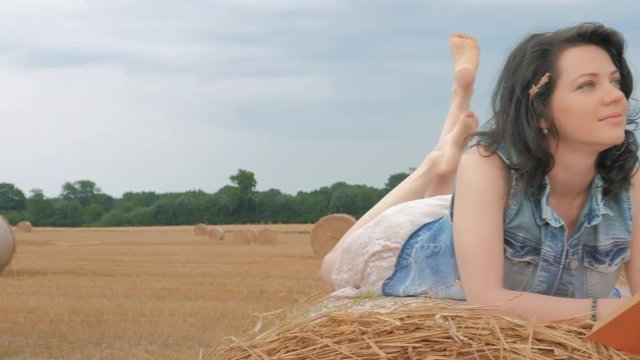 Beautiful woman Reading a book and lying on a haystack