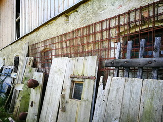 Ansammung alter Holztüren und Gegenstände aus einem Kuhstall vor einem alten Bauernhaus auf dem...