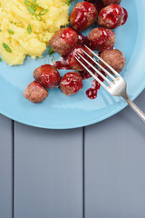 Traditional Sweden dish. Beef meatballs with sour berry sauce and mashed potatoes on blue plate above view