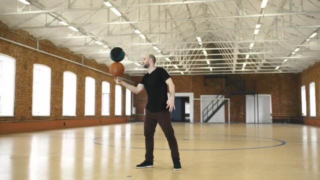 Young man spinning 2 balls on finger. Slow motion
