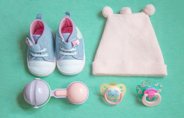 Fototapeta na wymiar baby stuff is on a blue background. top view closeup. things little girl, pacifier, rattle, hat, and shoes.newborn baby necessities
