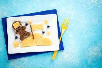 Kids breakfast with creative sandwich on blue background top view, copy space. Funny toast with cheese and berries in the shape astronaut for childrens breakfast or lunch - Powered by Adobe