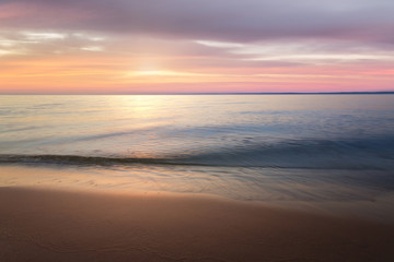 Fototapeta na wymiar calm water on a background quiet sunset / wild beach dawn alone