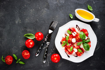 Salad caprese. Cheese mozzarella, tomatoes, olive oil and basil herb leaves on concrete background. Healthy eating vegetable vegetarian food