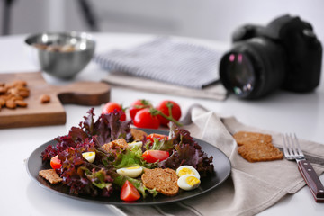 Composition with salad and professional camera on white table