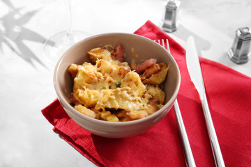 Bowl with tasty baked potato, bacon and cheese on table
