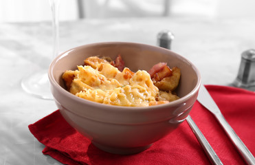 Bowl with tasty baked potato, bacon and cheese on table