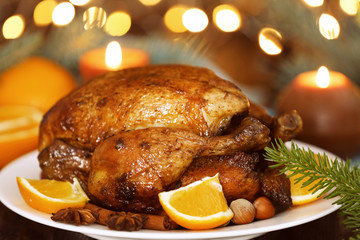 Plate with tasty whole roasted turkey on table against defocused lights