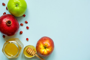 Honey, apple and pomegranate for Rosh Hashanah on blue background