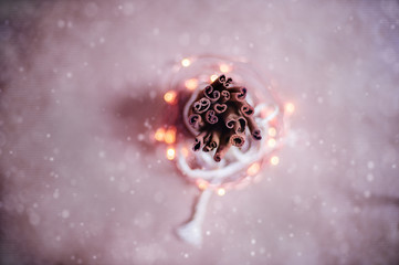 Top view to cinnamon sticks tightened together. Snow blur and Christmas bokeh lights background. Vintage Toned image.