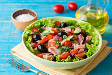 Salad with vegetables and tuna on rustic blue wooden table