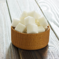 Sugar cubes in bowl on wooden table. White sugar cubes in bowl.