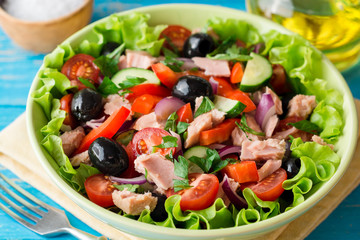 Salad with vegetables and tuna on rustic blue wooden table