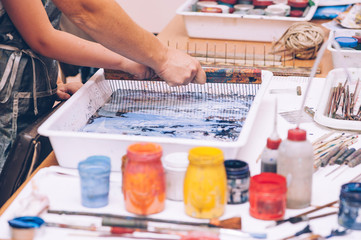 The master teaches the girl the technique of ebru. Hands close up