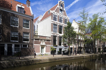 Traditional dutch buildings, their reflections in canal's water and sky as background